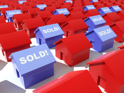 Blue toy houses with the word "SOLD" on them in a field of red toy houses on a white background